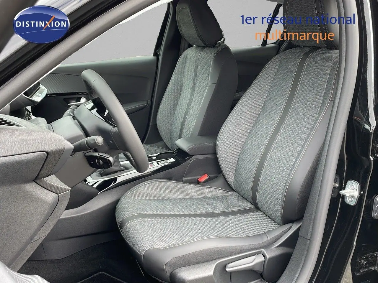 Vue intérieure côté conducteur de la Peugeot 208 2024 noire, sièges tissu gris avec surpiqûres et volant compact.