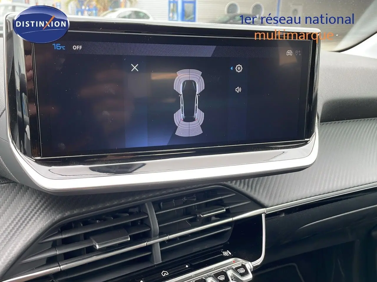 Écran tactile central affichant l'aide au stationnement dans l'habitacle d'une Peugeot 208 noire.