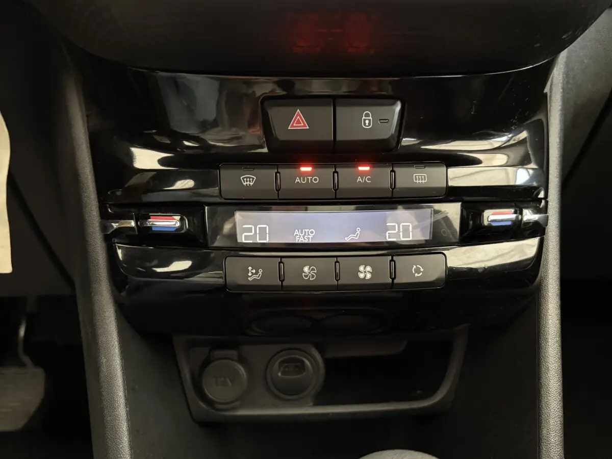 Panneau de commande de la climatisation digitale noir brillant dans l’habitacle du Peugeot 2008 rouge, version Allure.