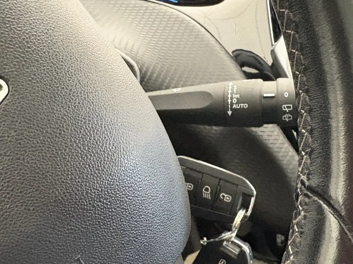 Gros plan sur le volant cuir noir et la commande d’essuie-glace du Peugeot 2008 Puretech 110 rouge de 2019.