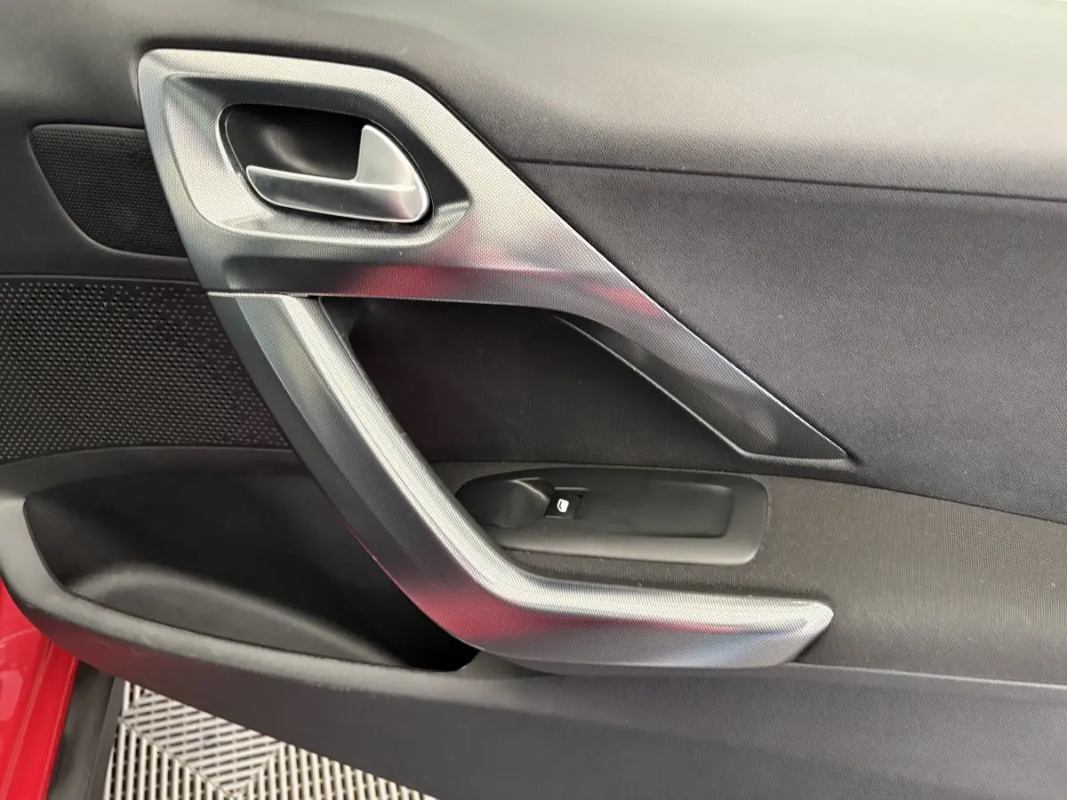 Poignée intérieure côté gauche de la porte avant d'un Peugeot 2008 rouge, finition Allure 2019.