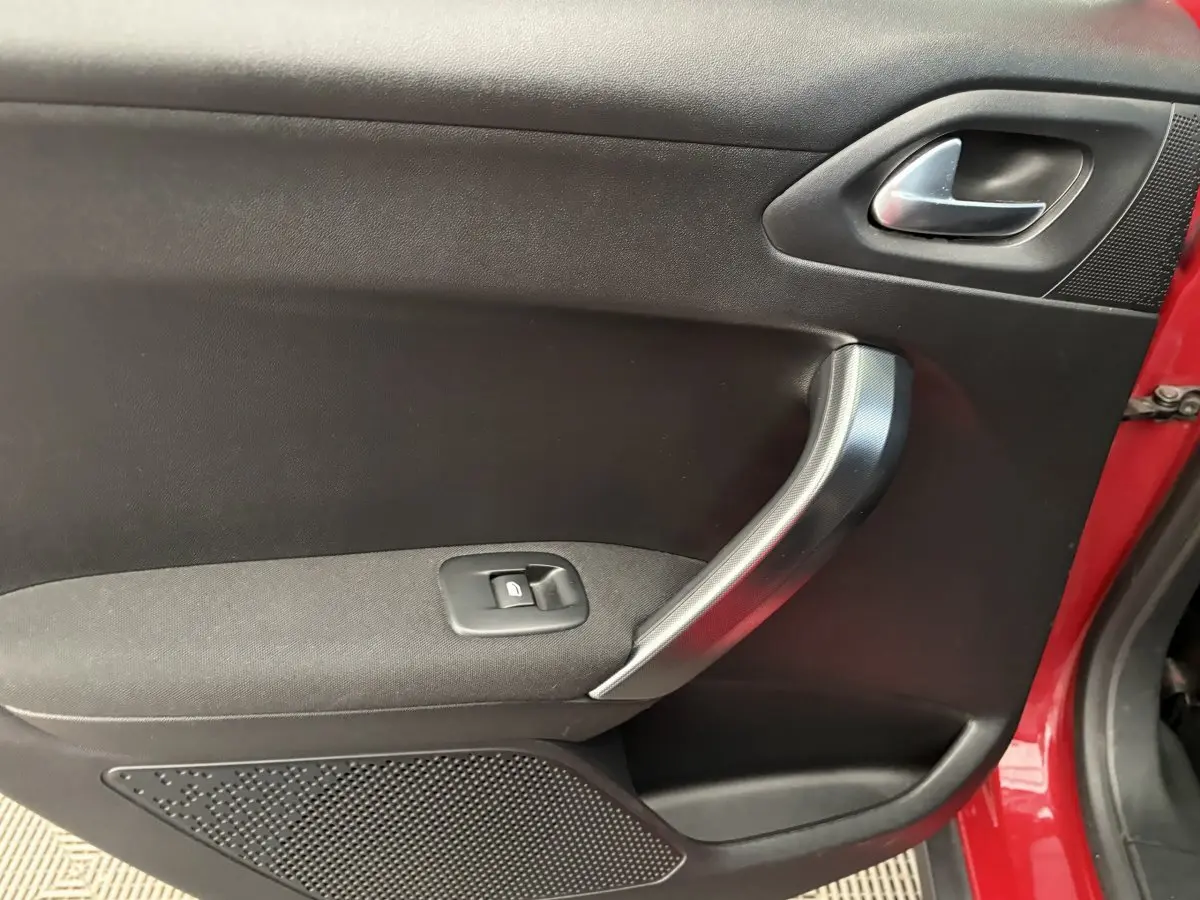 Vue rapprochée de la porte côté gauche rouge d'un Peugeot 2008 2019 avec poignée argentée et bouton de lève-vitre.