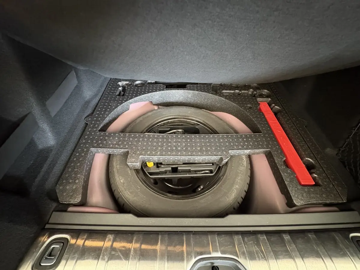 Roue de secours et kit de réparation logés sous le plancher du coffre du Peugeot 2008 rouge, vue intérieure du coffre.