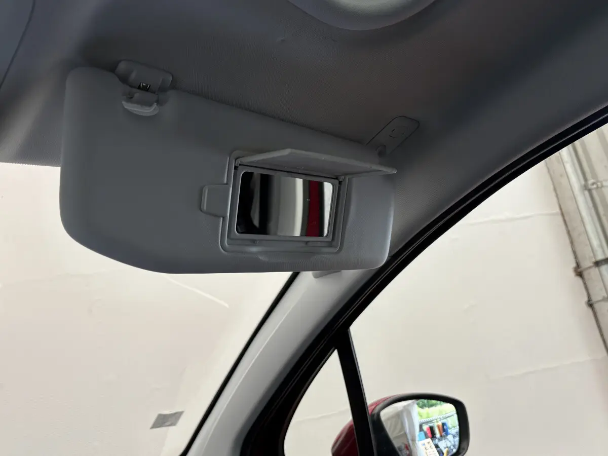 Miroir de courtoisie ouvert sur le pare-soleil côté conducteur dans le Peugeot 2008 rouge, vue intérieure avant droite.