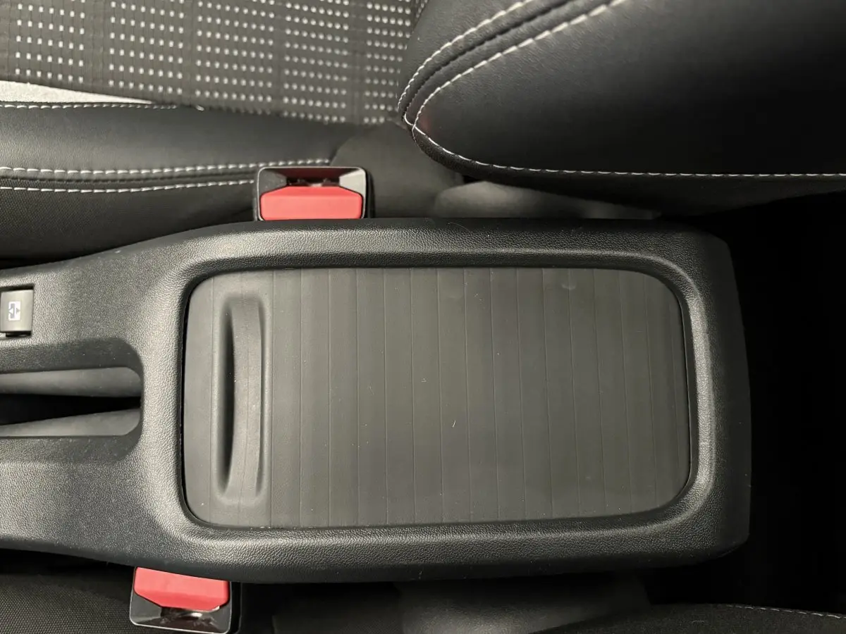 Vue rapprochée du rangement central noir entre les sièges avant d’un Peugeot 2008 rouge modèle 2019.