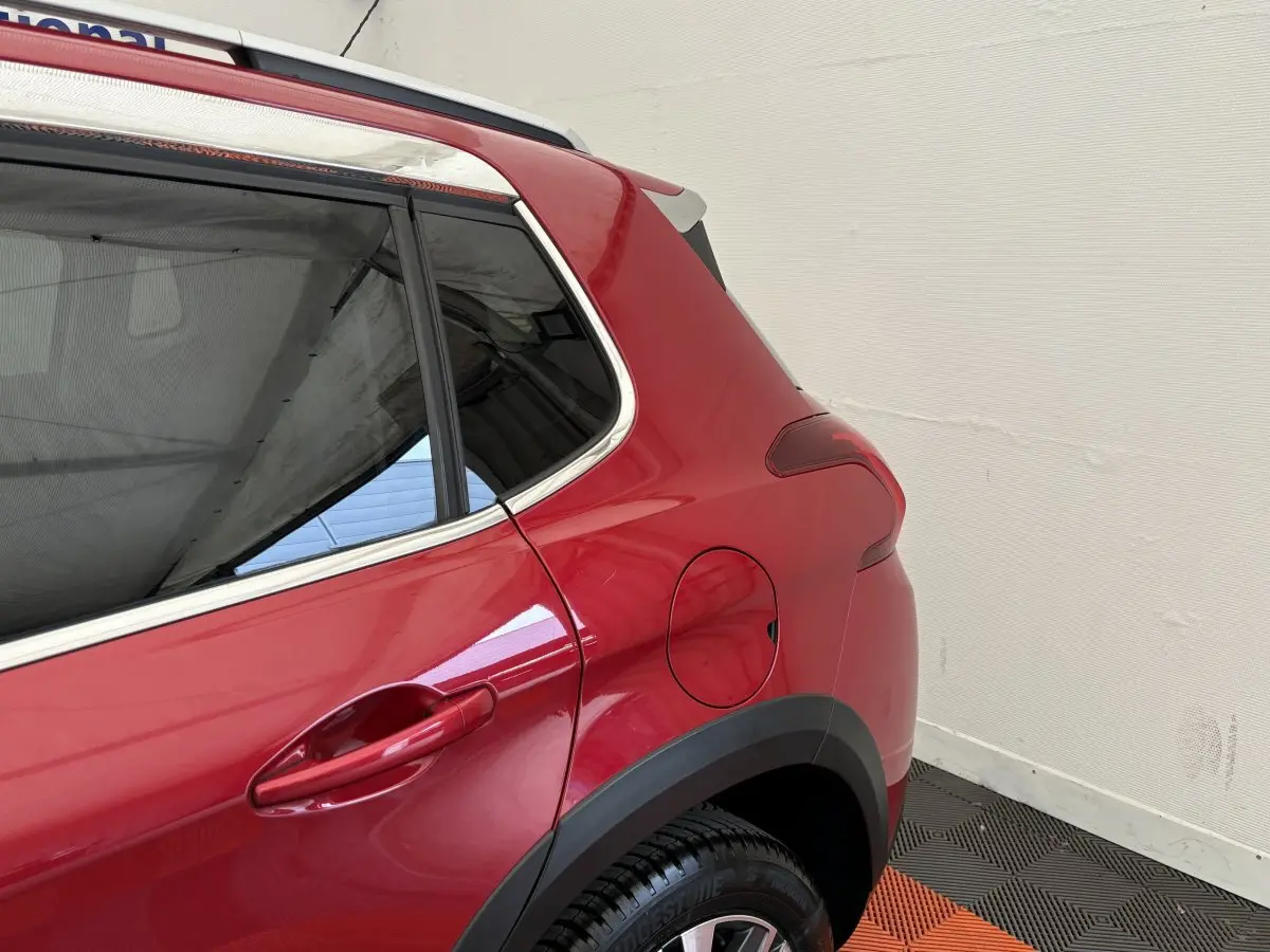 Vue rapprochée du côté arrière gauche d’un Peugeot 2008 rouge, mettant en valeur la porte et la trappe à carburant.