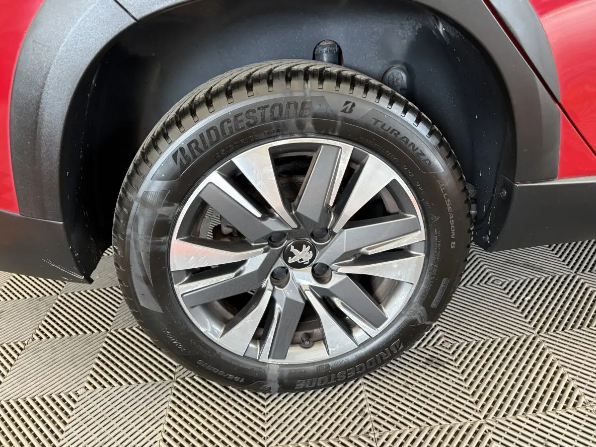Gros plan sur la roue avant droite avec jante alliage et carrosserie rouge du Peugeot 2008 Puretech 110 Allure 2019.
