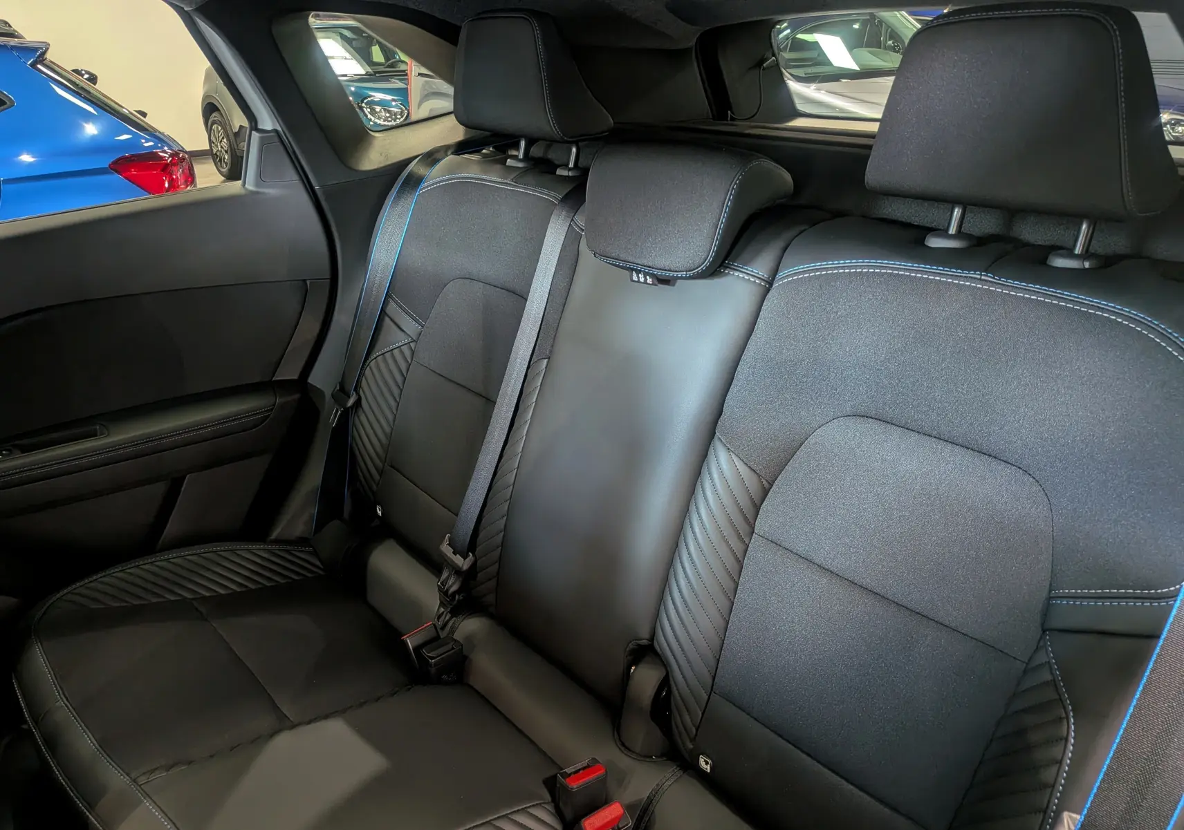 Vue intérieure arrière droite des sièges noirs avec surpiqûres bleues du Renault Symbioz E-TECH Full Hybrid 2026.