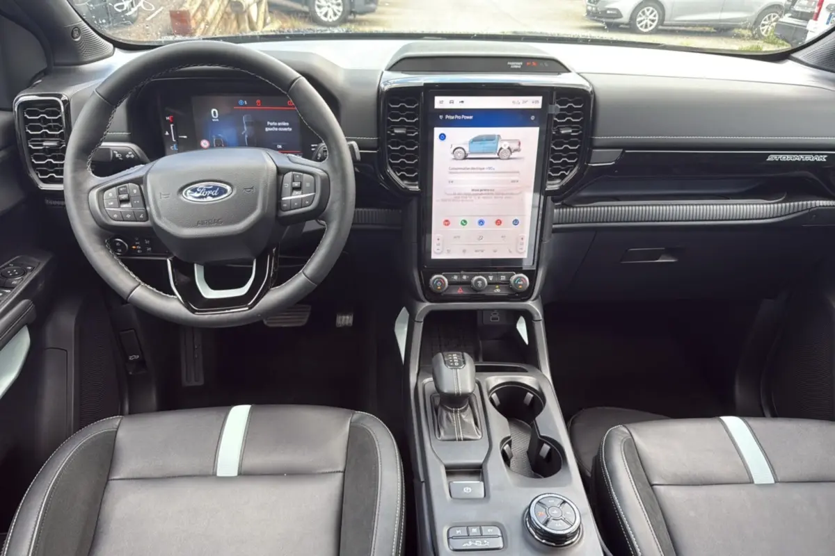 Vue intérieure frontale du Ford Ranger 2.3 PHEV avec tableau de bord noir et écran tactile vertical central.