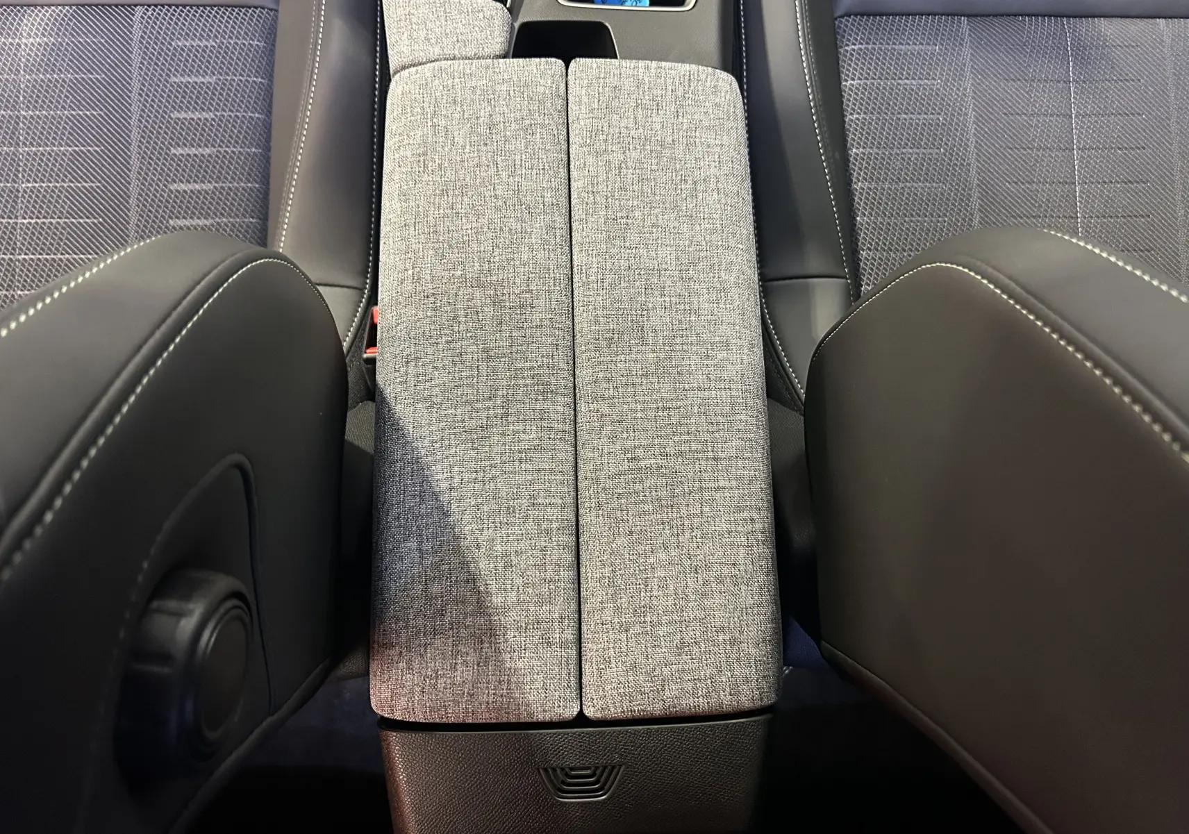Vue plongeante sur l'accoudoir central gris clair et les sièges en tissu gris du Peugeot 3008 Hybrid 2026.