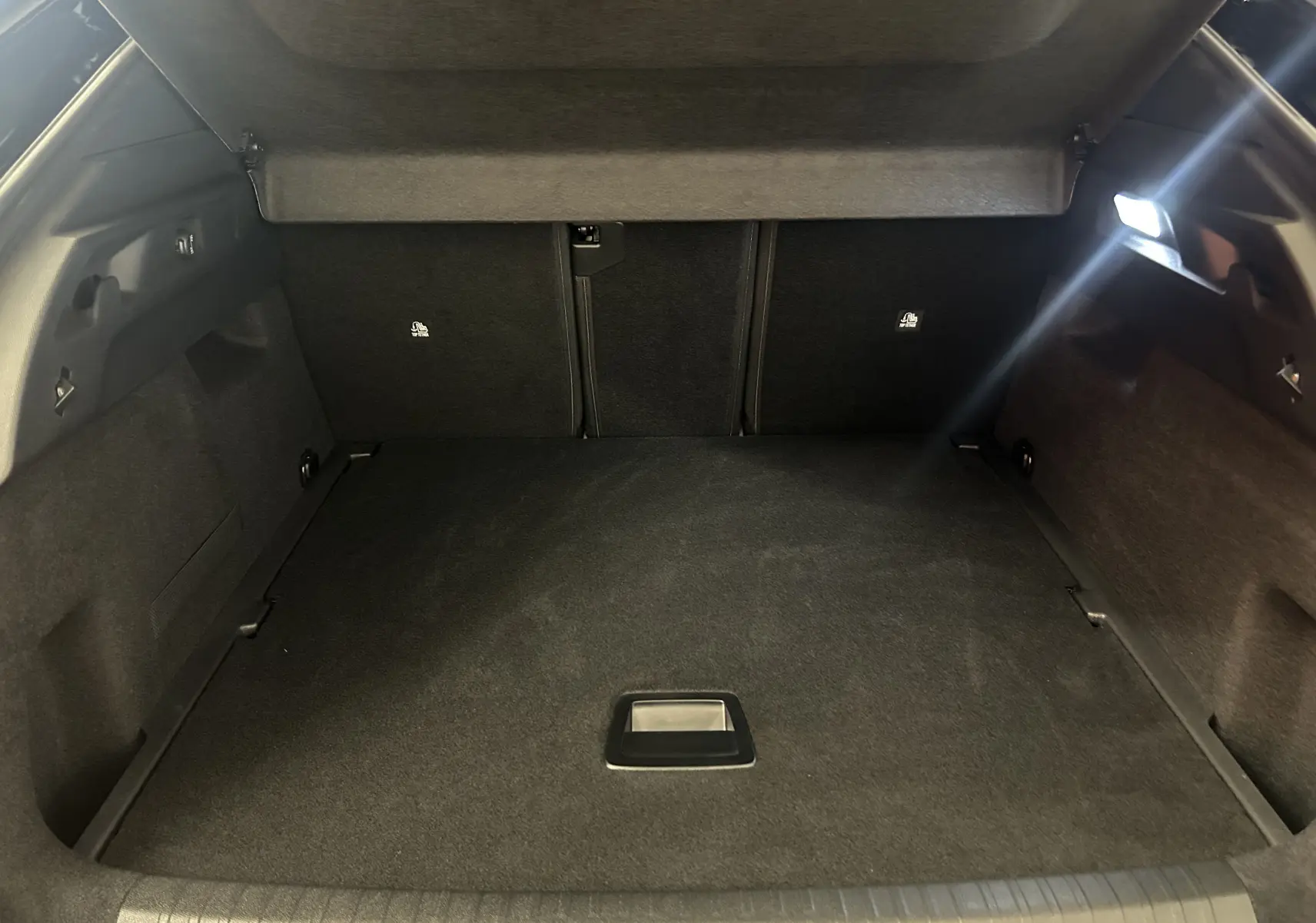 Coffre ouvert vu de l'intérieur du Peugeot 3008 gris Artense, avec éclairage latéral et habillage noir.