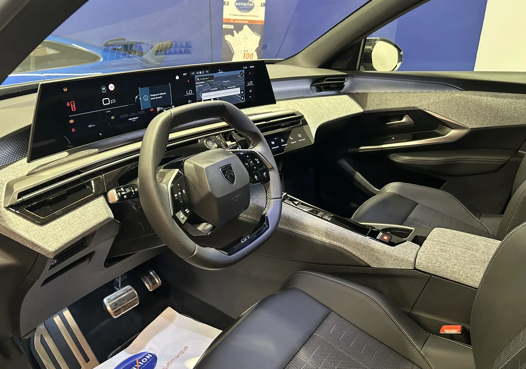 Vue intérieure côté conducteur du Peugeot 3008 III Hybrid avec tableau de bord numérique et finitions tissu gris et cuir noir.