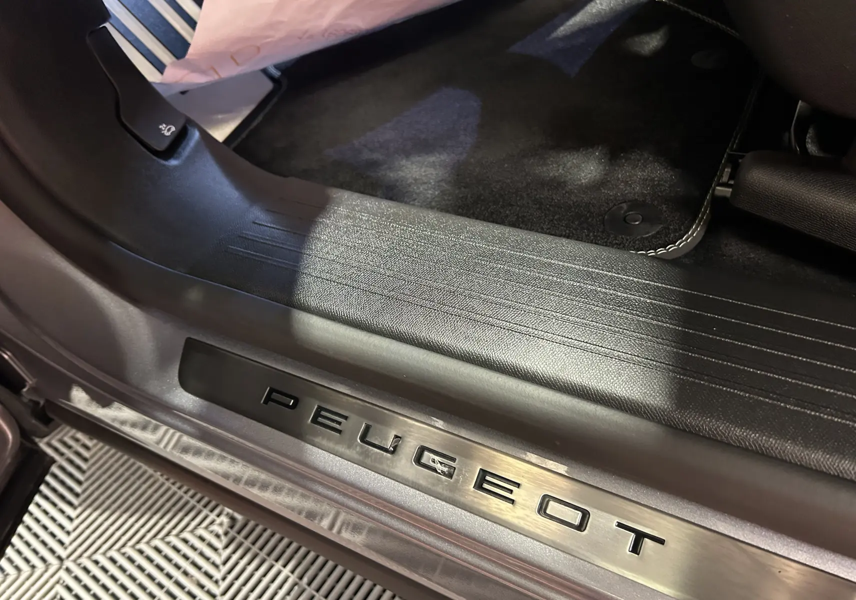 Gros plan sur la plaque de seuil de porte Peugeot à l'entrée côté conducteur, intérieur noir du 3008 gris Artense.