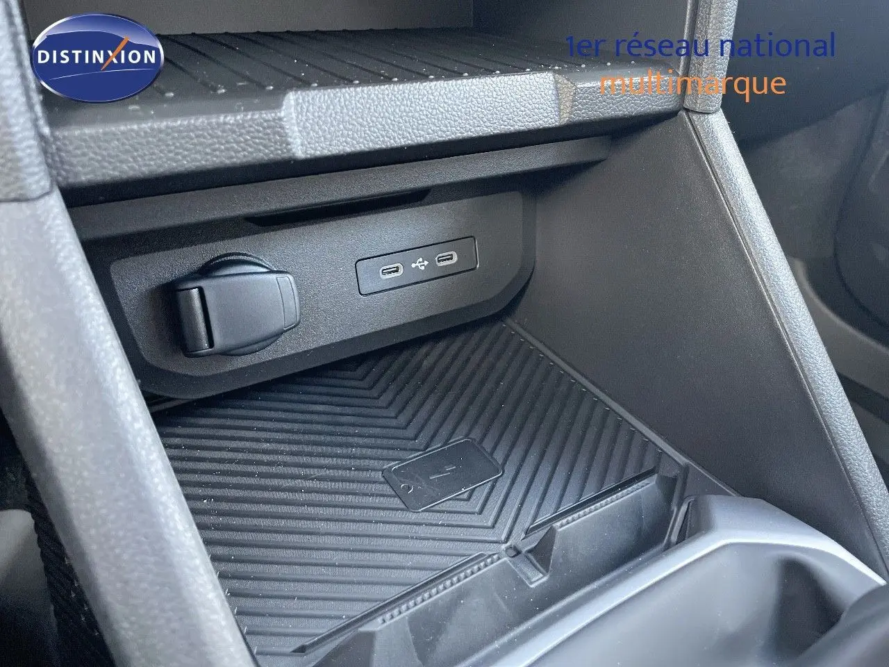 Prise USB et prise 12V dans le rangement central avant du Dacia Duster 2024 noir métal, côté passager.