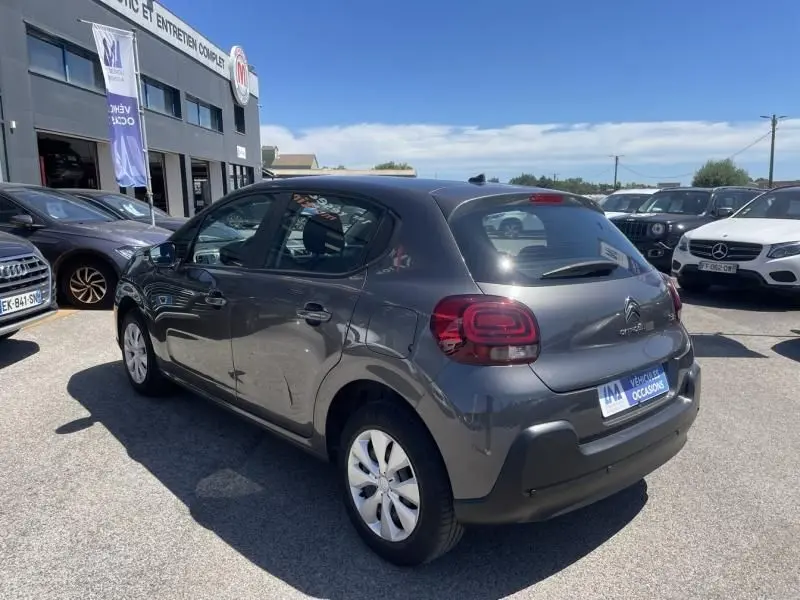 Citroën C3 82 CV Feel gris foncé métal vue 3/4 arrière droit sur parking ensoleillé avec plusieurs véhicules autour