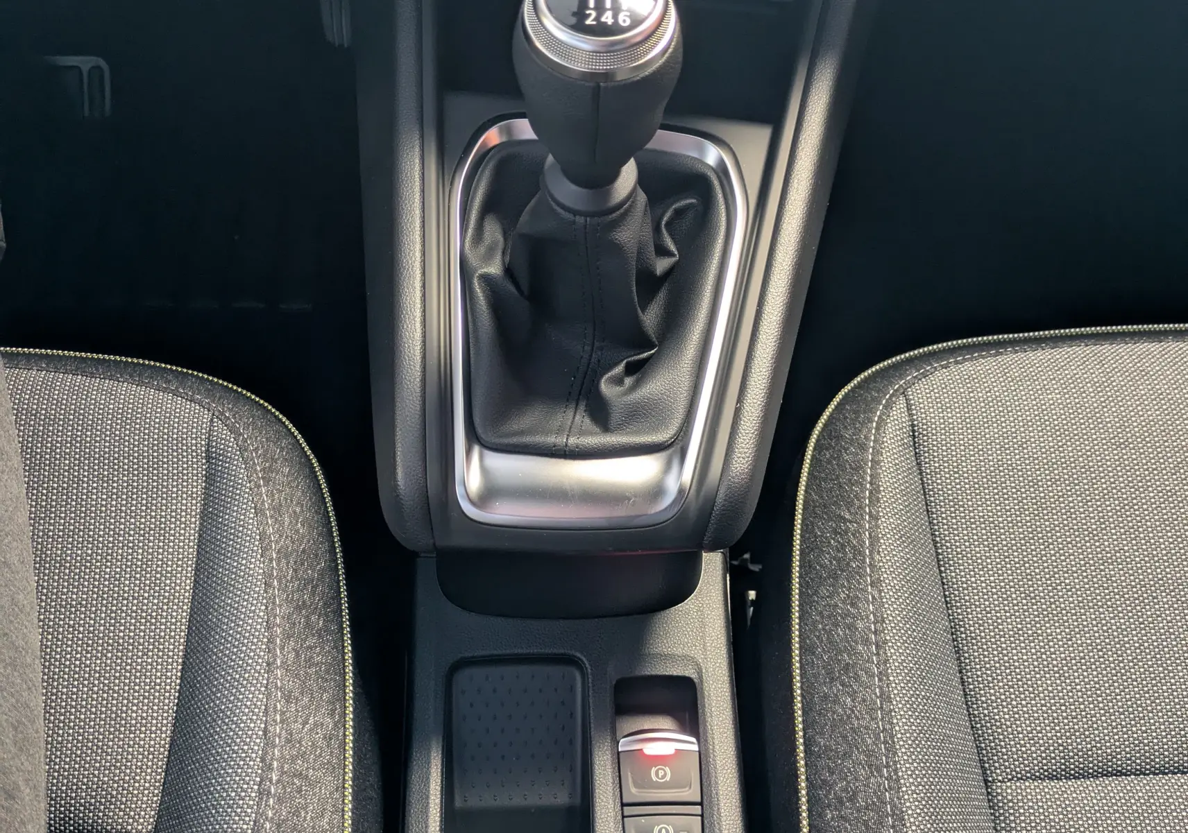 Vue rapprochée de la console centrale du Renault Captur 2025 avec levier de vitesse manuel et sièges tissu gris.