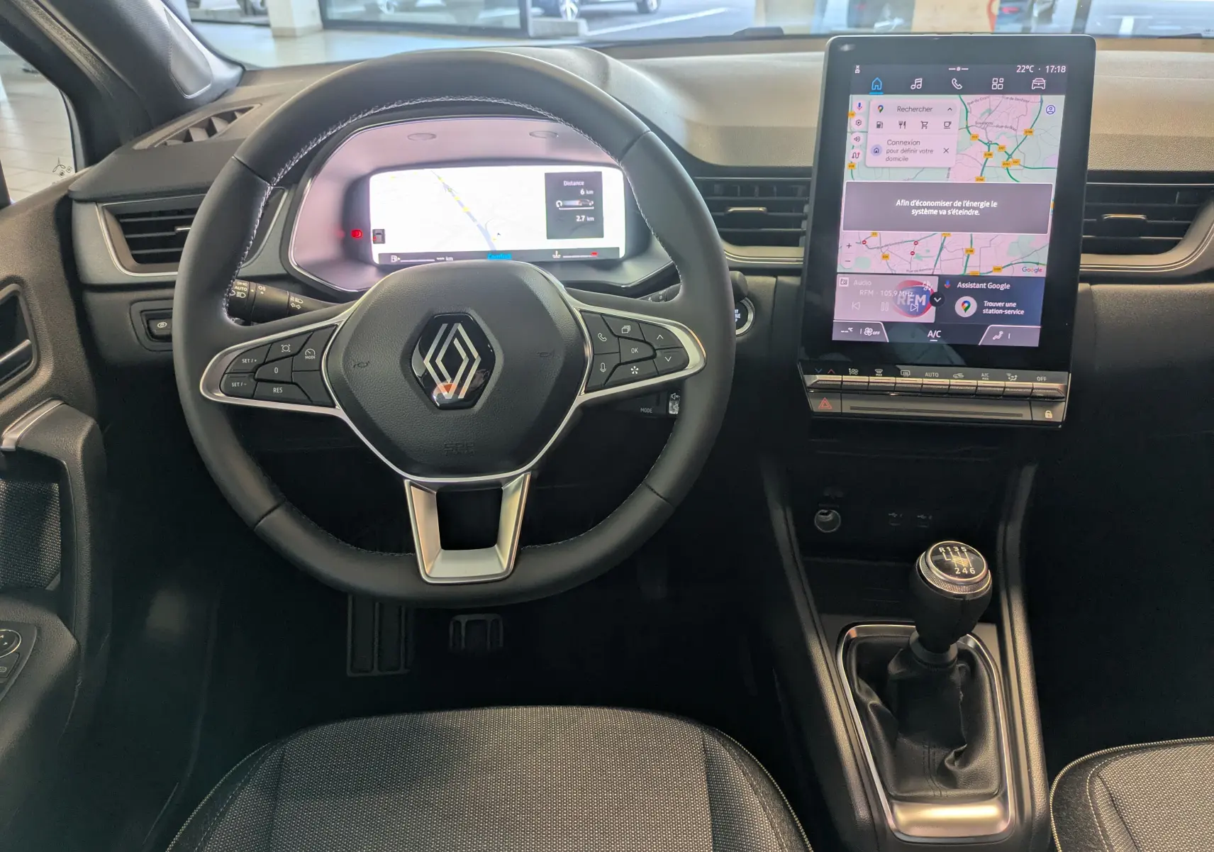Vue intérieure frontale du tableau de bord du Renault Captur 2025 avec volant, écran numérique et levier de boîte manuelle.