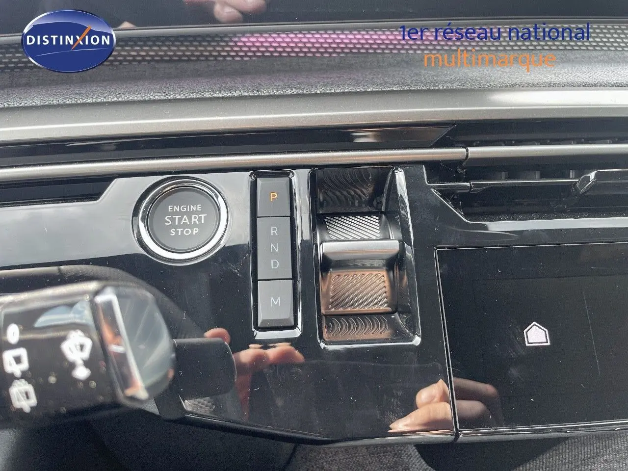 Gros plan sur la console centrale noire perle métal du Peugeot 5008 Hybrid 2025 avec bouton start et commandes de boîte auto.