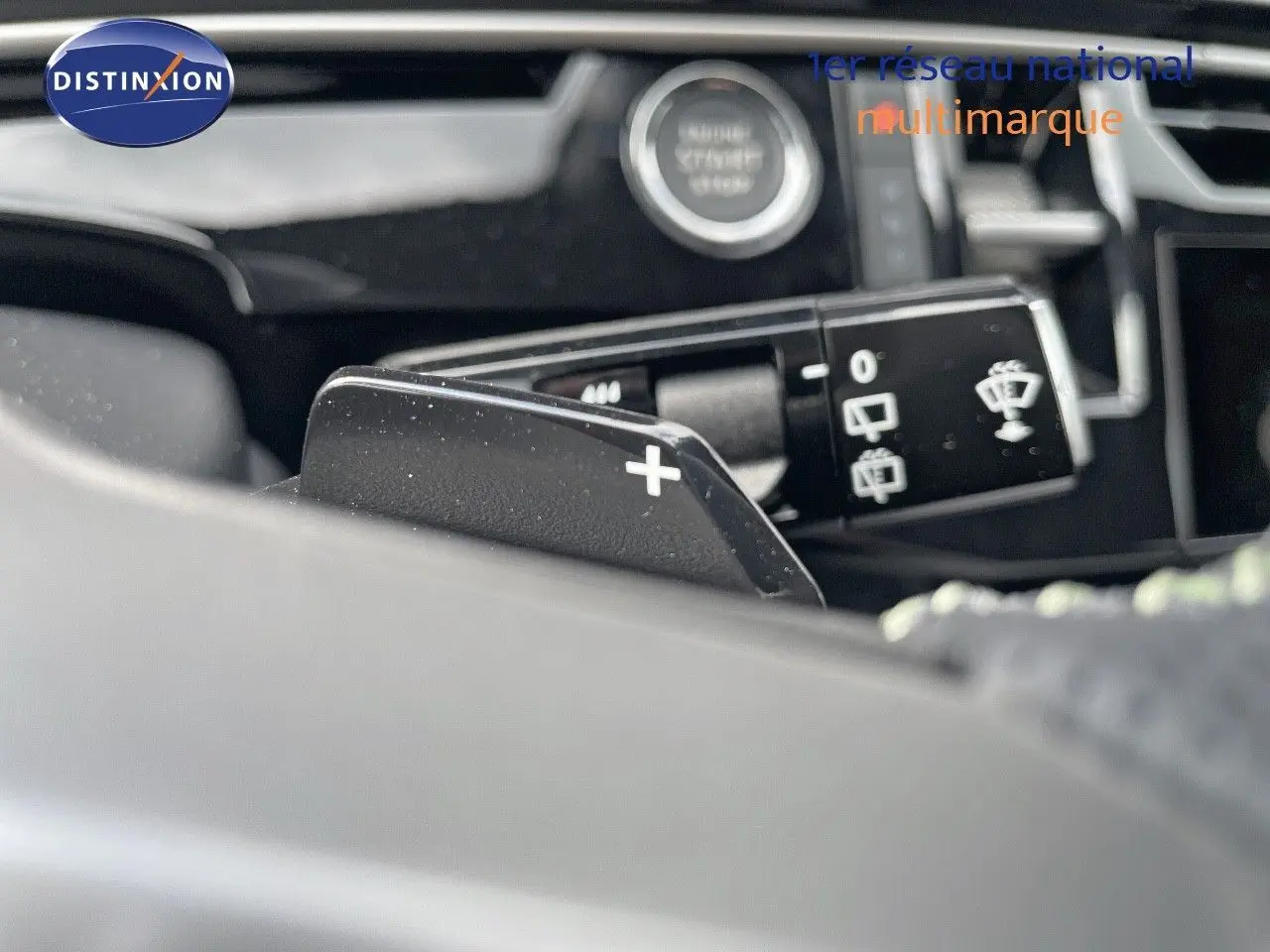 Gros plan sur la palette de changement de vitesse + au volant d’un Peugeot 5008 noir perle hybride 2025.