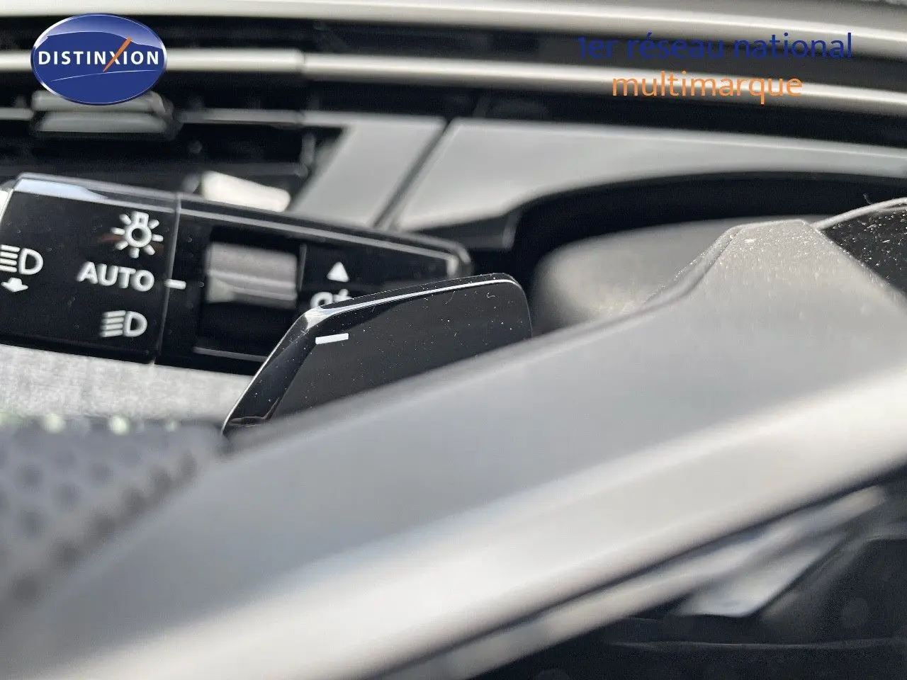 Gros plan sur la palette de changement de vitesse et le commodo des phares du Peugeot 5008 noir perle métal.