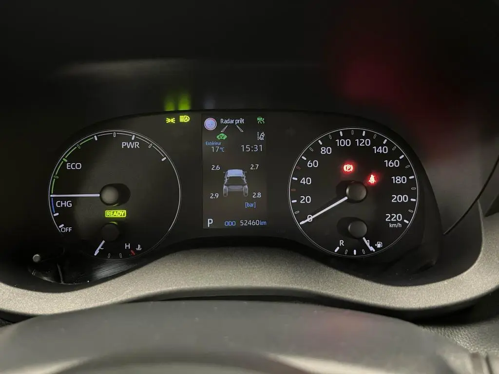 Tableau de bord de Mazda2 hybride 2023 montrant compteurs analogiques, écran central avec pression pneus et voyants allumés.