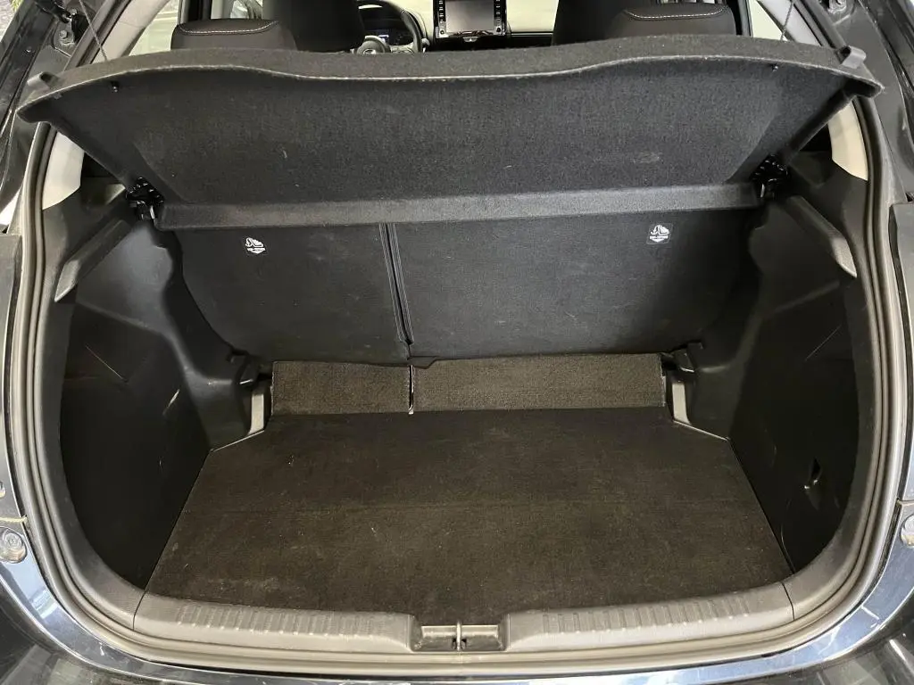Coffre ouvert vu de l'arrière d'une Mazda2 noire 2023, montrant l'espace de chargement et la tablette cache-bagages.