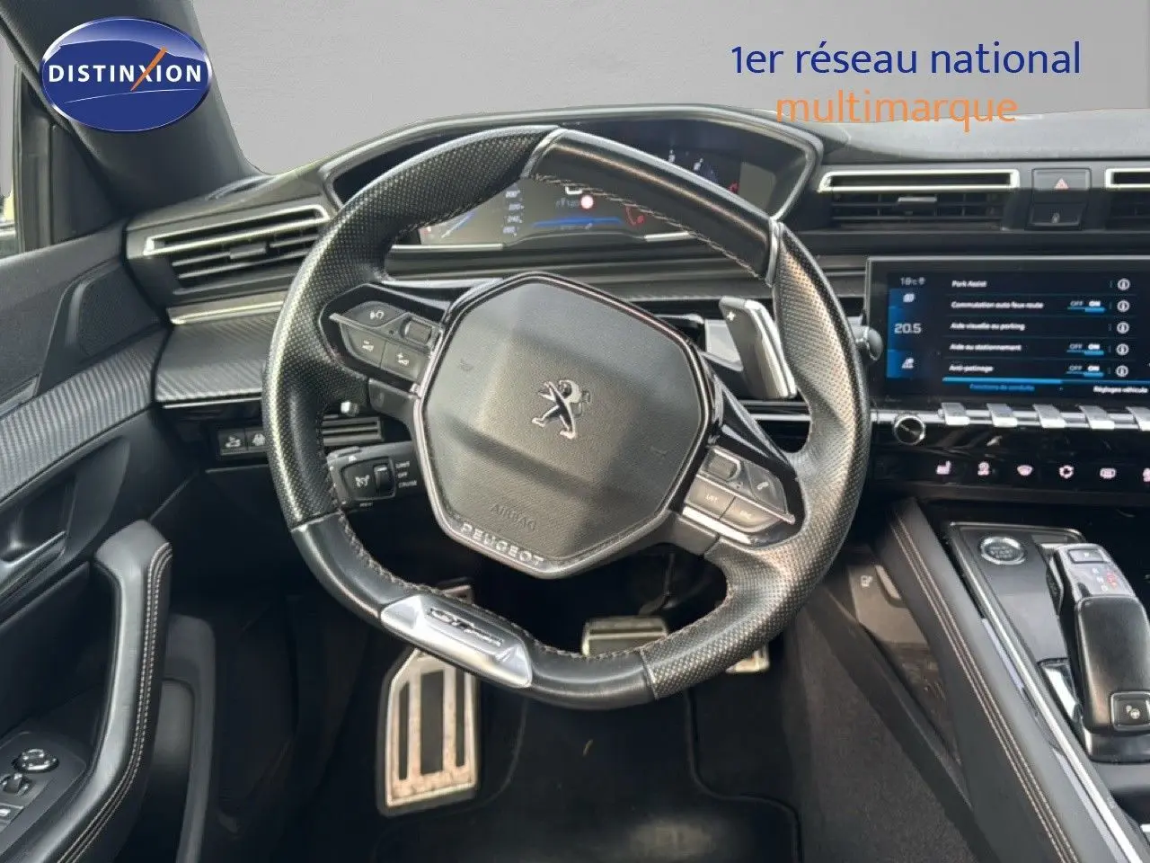 Vue intérieure centrée sur le volant cuir noir de la Peugeot 508 gris platinium avec tableau de bord et écran tactile.