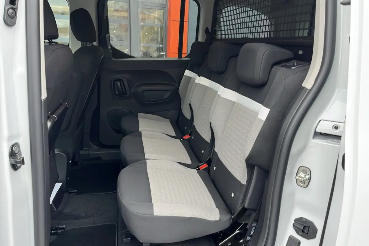 Vue latérale intérieure du siège arrière 3 places en tissu gris et noir du Citroën Berlingo Kaolin White 2026 avec grille de séparation.