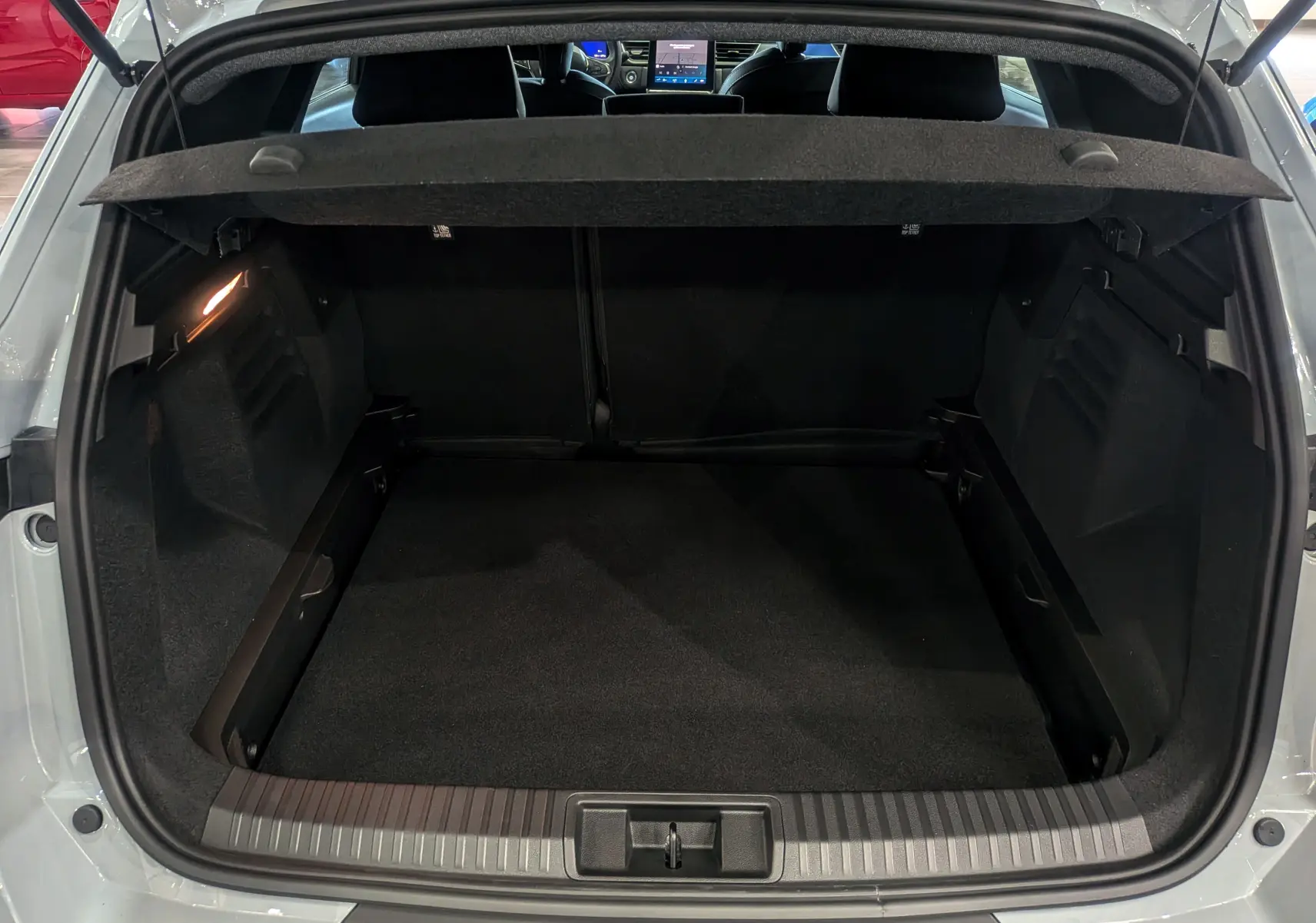 Coffre ouvert vu de l'arrière d'une Renault Symbioz gris Rafale, intérieur noir et tablette cache-bagages visible.