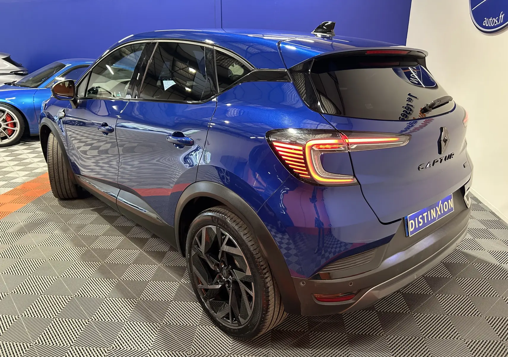 Vue 3/4 arrière droite du Renault Captur II Ph.2 E-Tech Full Hybrid 145 en bleu Iron avec jantes noires et feux allumés.