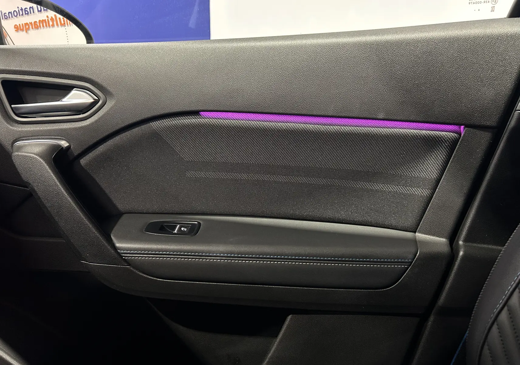 Vue intérieure côté droit de la porte du Renault Captur II Ph.2 en noir avec éclairage d’ambiance violet et bouton de lève-vitre.