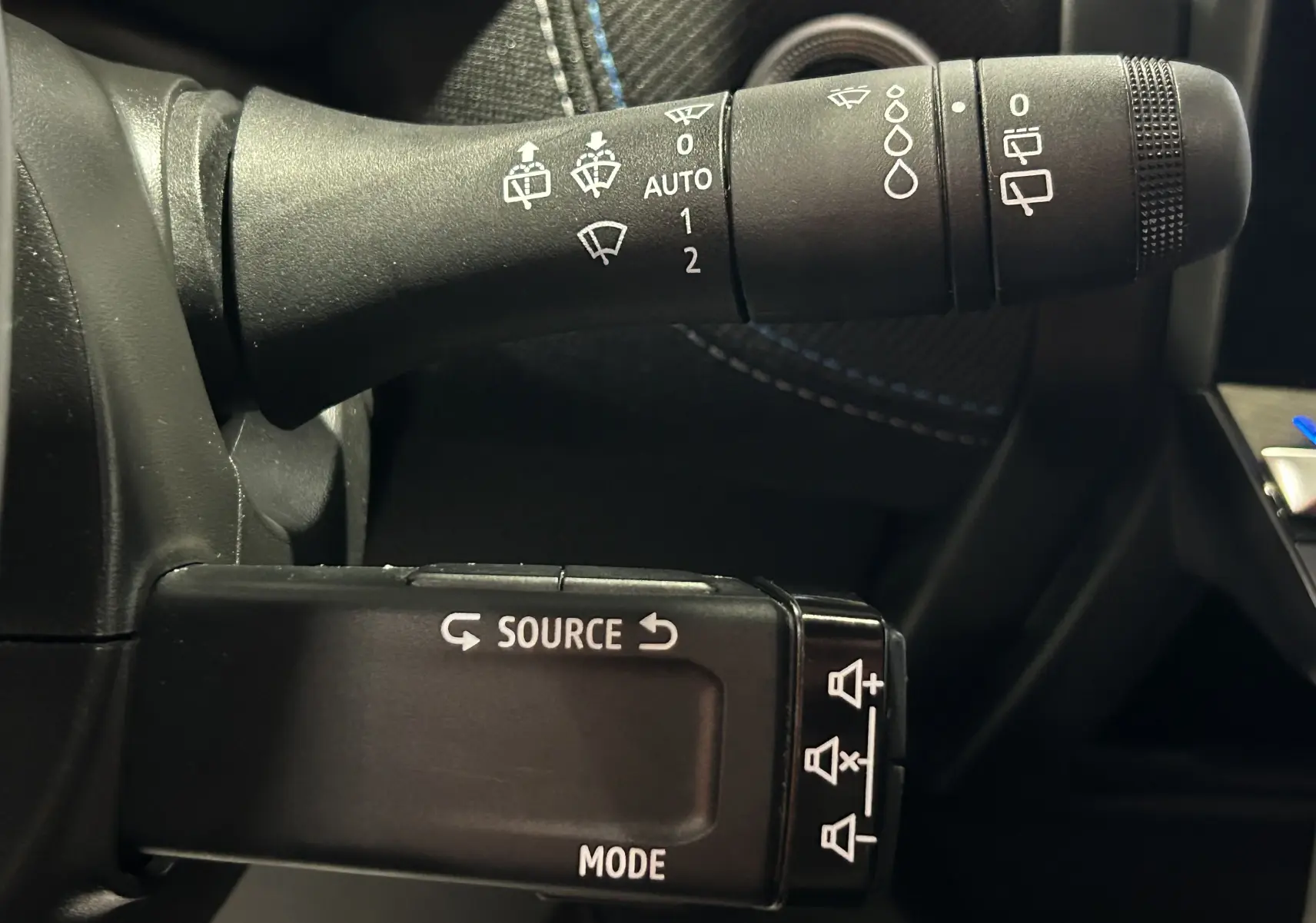 Gros plan sur les commandes au volant du Renault Captur II Ph.2, mettant en valeur les fonctions essuie-glace et audio.