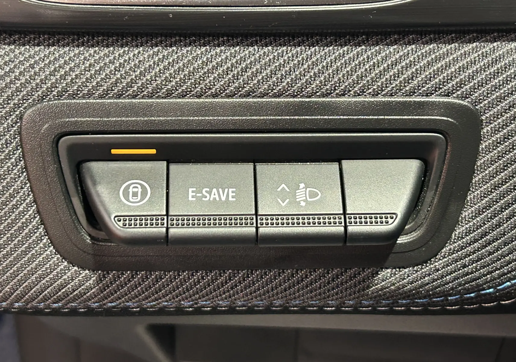 Gros plan sur les boutons de commande E-SAVE et réglage des phares du tableau de bord du Renault Captur bleu Iron.