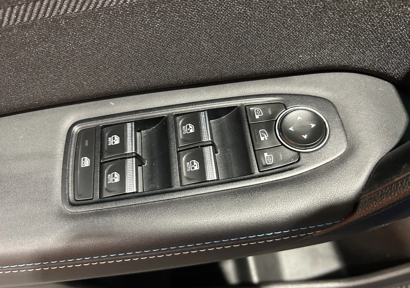 Gros plan sur les commandes des vitres électriques et rétroviseurs côté gauche d’un Renault Captur II Ph.2 bleu Iron.