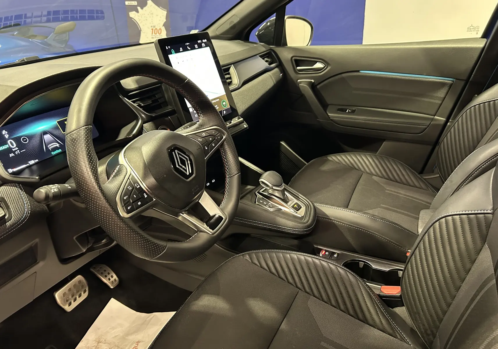 Vue intérieure côté conducteur du Renault Captur bleu Iron 2025, sièges noirs avec logo Alpine brodé.