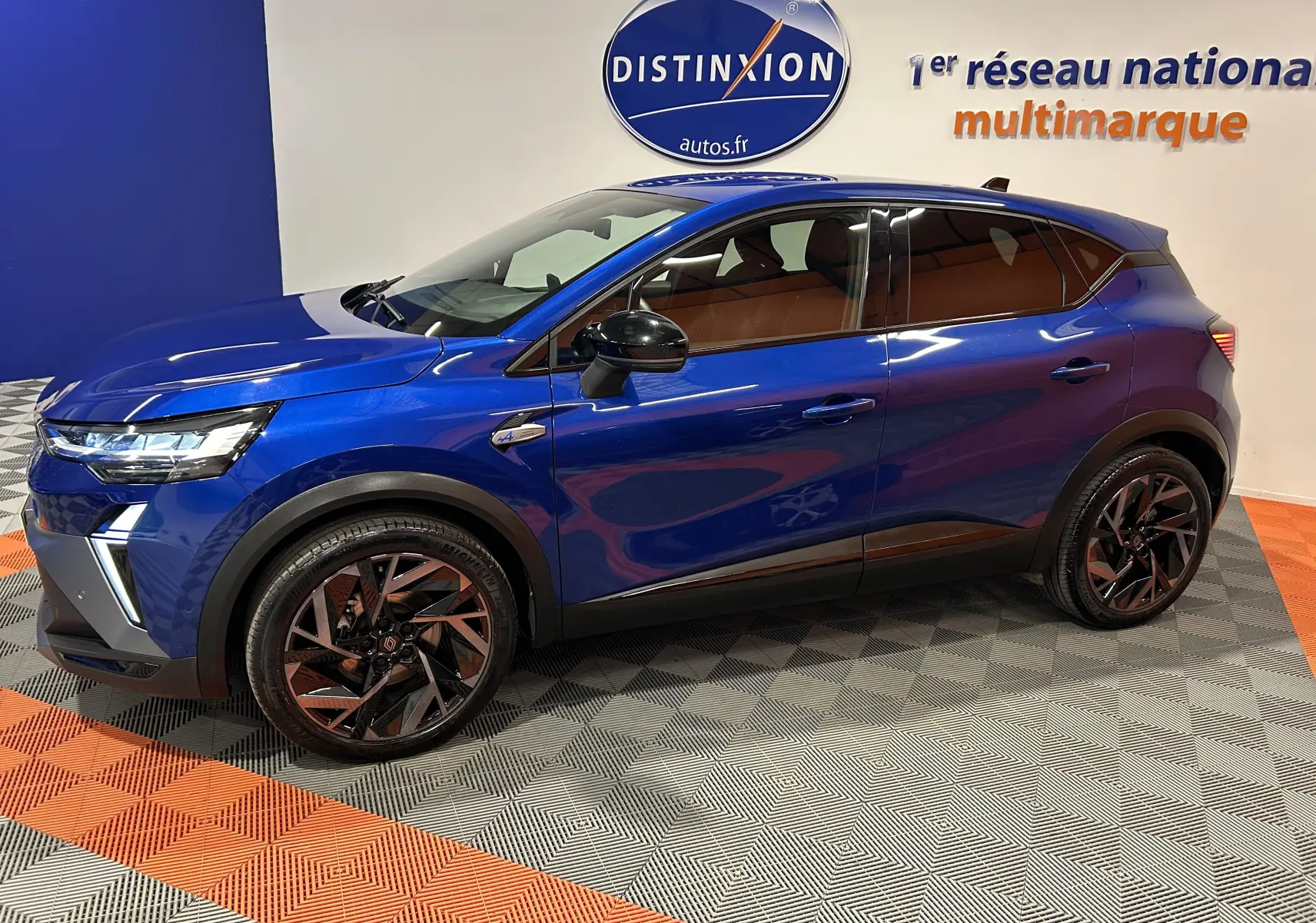 Renault Captur II Ph.2 E-Tech hybride bleu Iron en vue latérale gauche, jantes noires et intérieur marron visible.