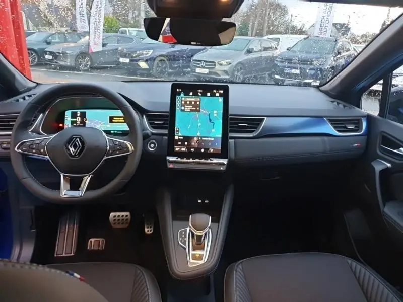 Vue intérieure avant du Renault Captur 1.6 E-Tech 2025 Bleu Iron, avec écran tactile vertical et volant multifonction cuir.
