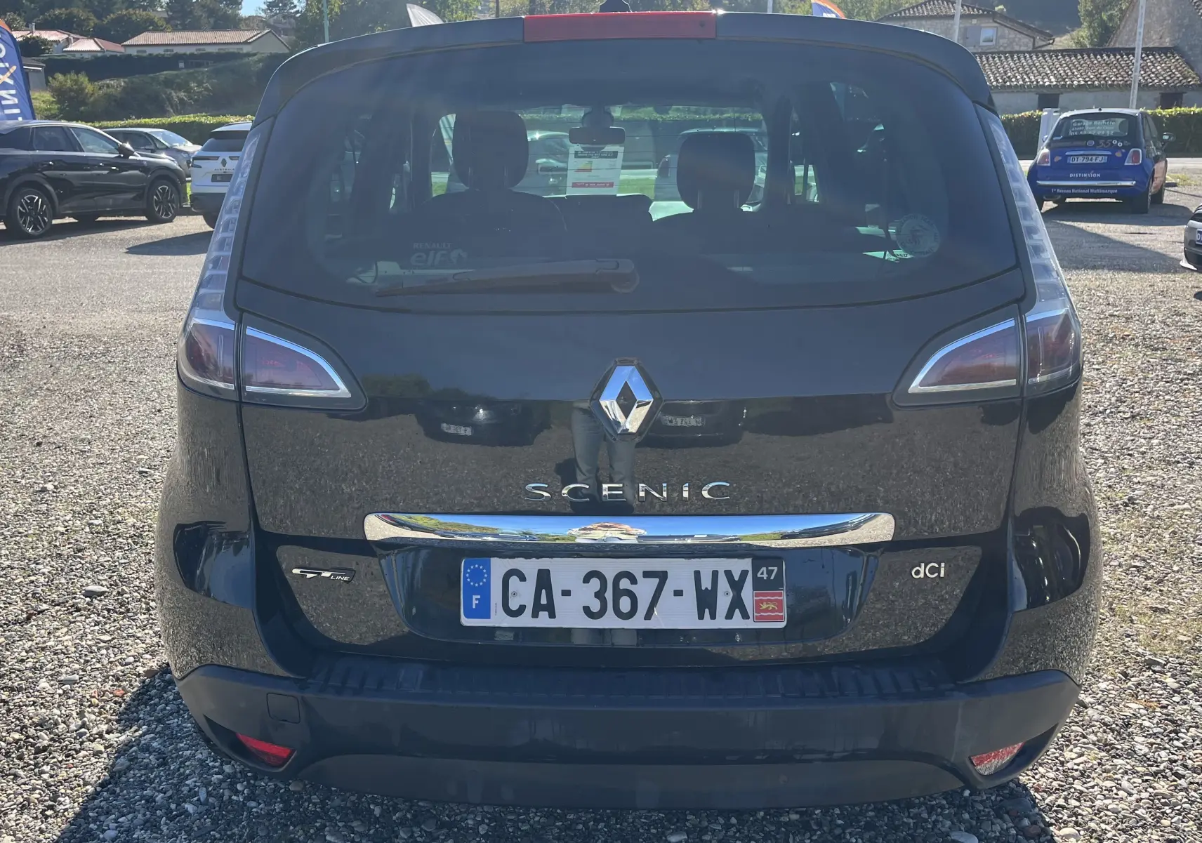 Vue arrière d'un Renault Scénic III noir de 2012 avec plaques françaises, feux arrière allongés et logo chromé central.