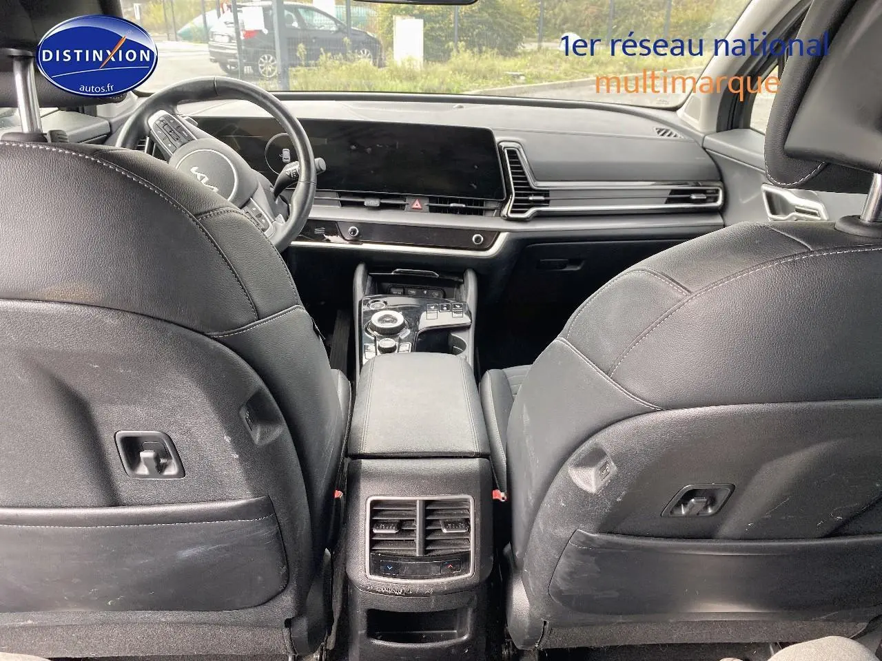 Vue arrière de l'intérieur noir du Kia Sportage 2023, montrant les sièges avant et la console centrale moderne.