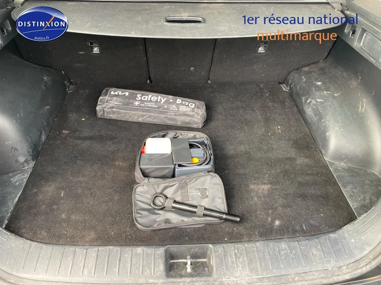Coffre noir du Kia Sportage 2023 avec kit de sécurité et accessoires de dépannage visibles.