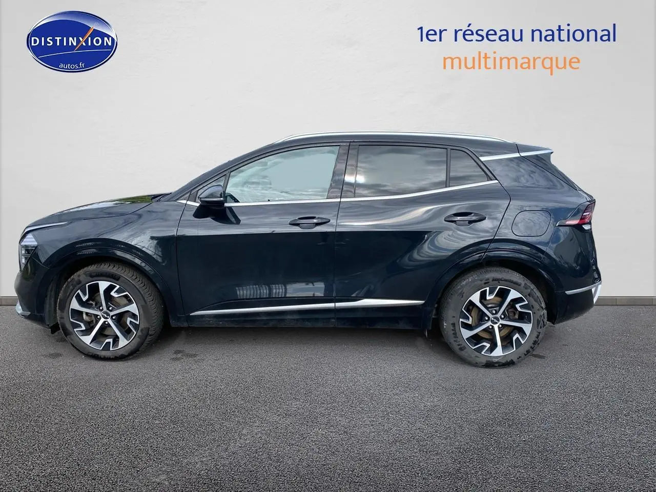 Profil côté gauche du SUV KIA SPORTAGE noir 2023 avec jantes alu et vitres teintées sur fond neutre.