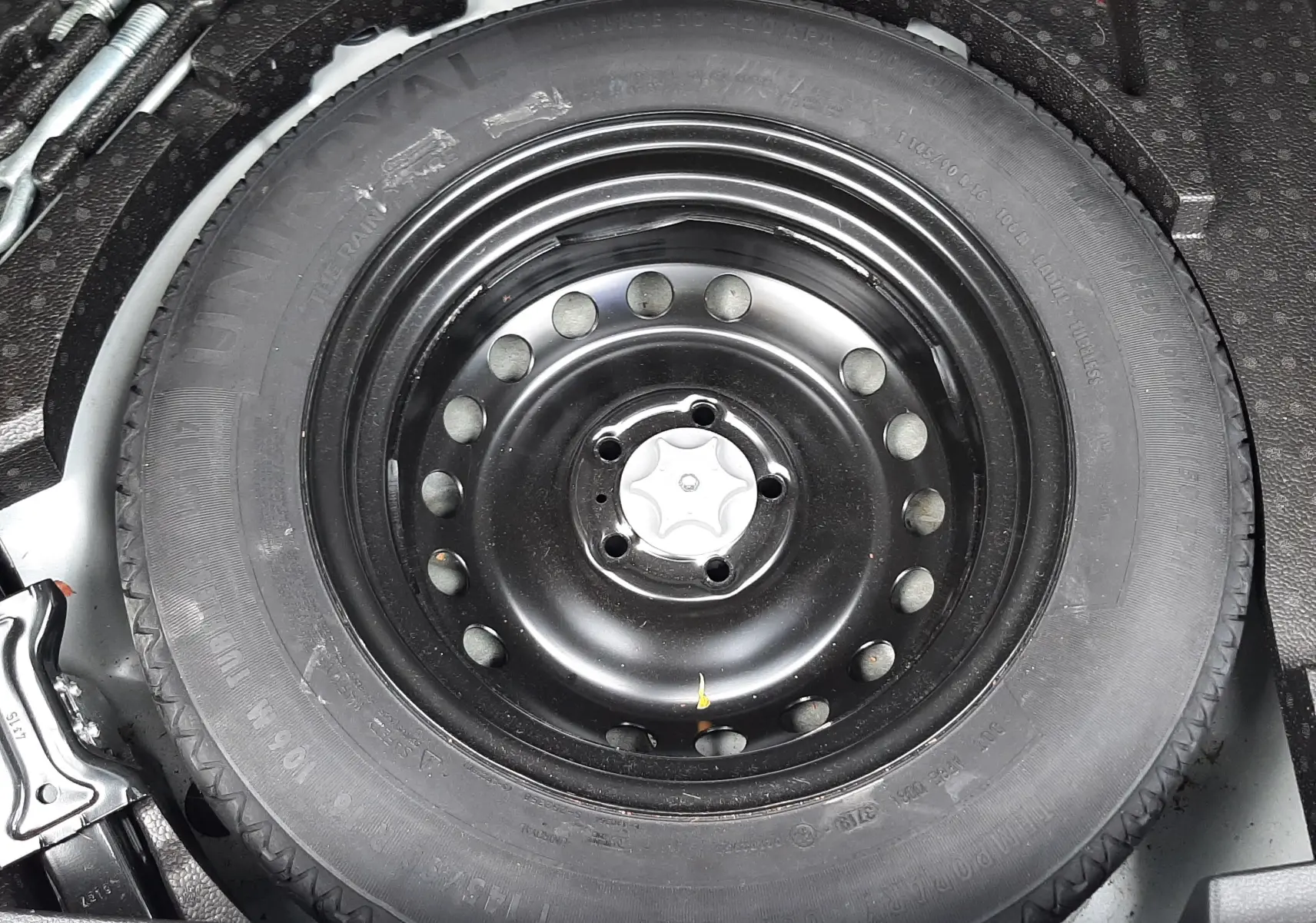 Gros plan sur la roue de secours noire dans le coffre du Nissan Qashqai blanc 2020.