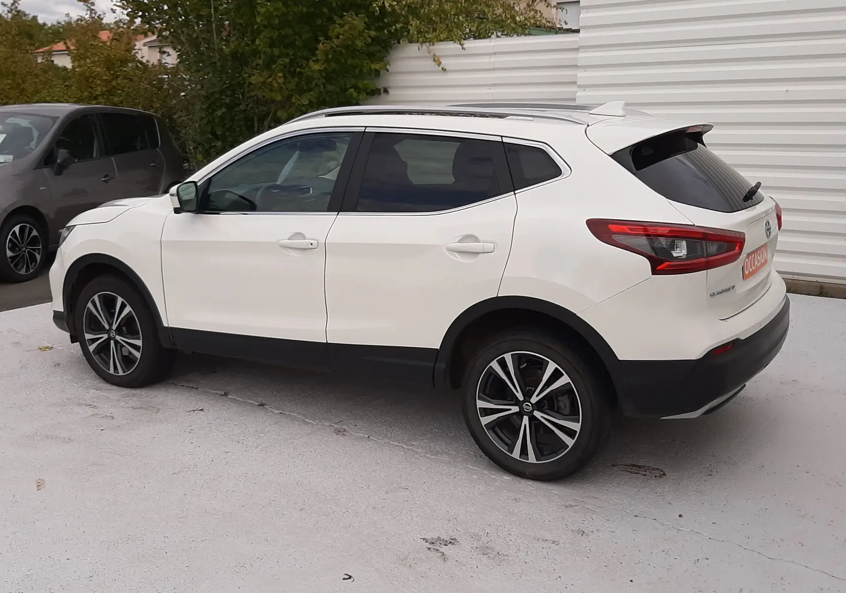 Nissan Qashqai blanc vue de profil côté gauche, avec jantes alliage bicolores et vitres teintées arrière.