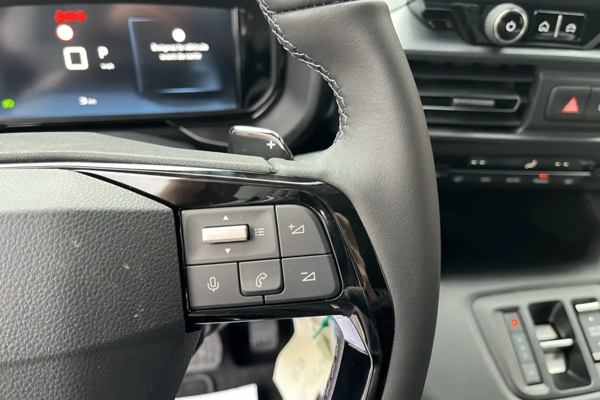 Gros plan sur le volant cuir multifonctions du Citroën Berlingo 2026, boutons de commande audio et téléphone visibles.