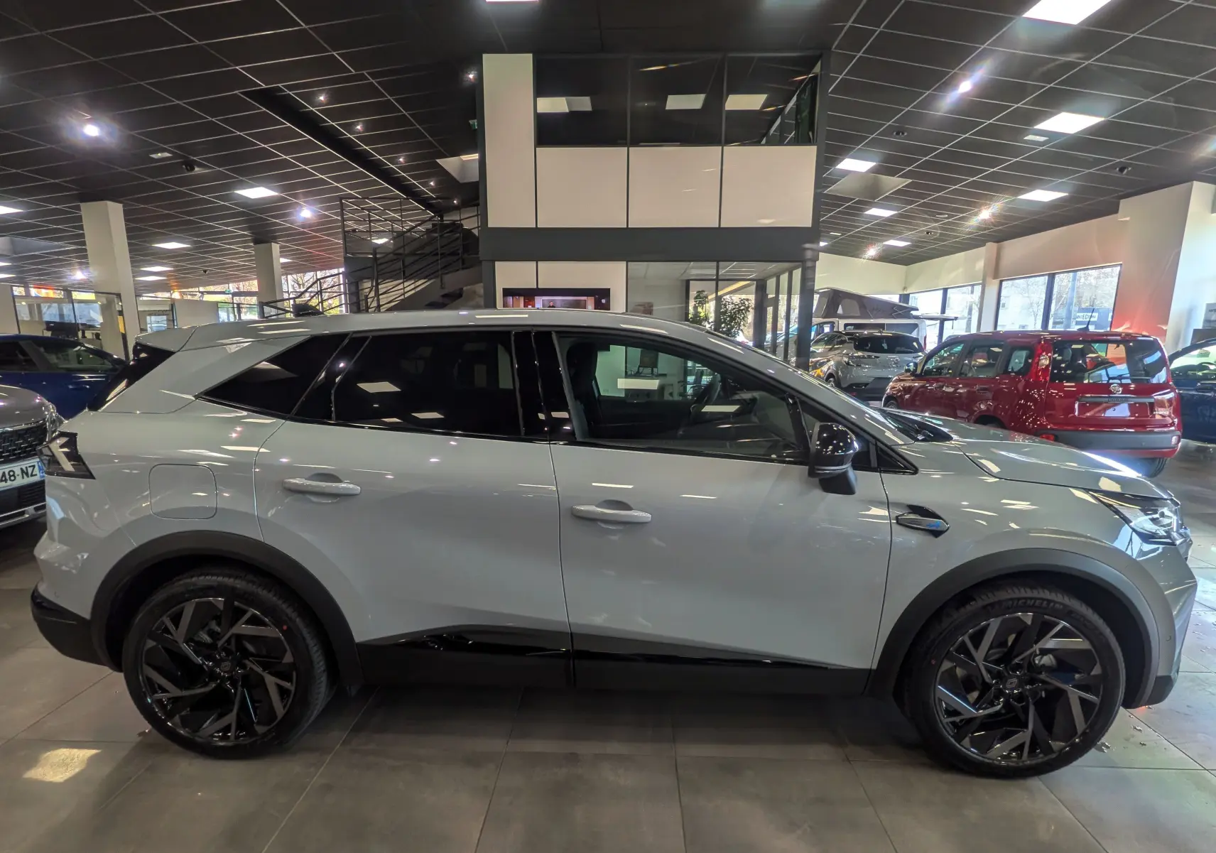 Vue de profil côté gauche d’un Renault SYMBIOZ gris Rafale en hybride essence, avec jantes noires et toit contrasté en showroom.