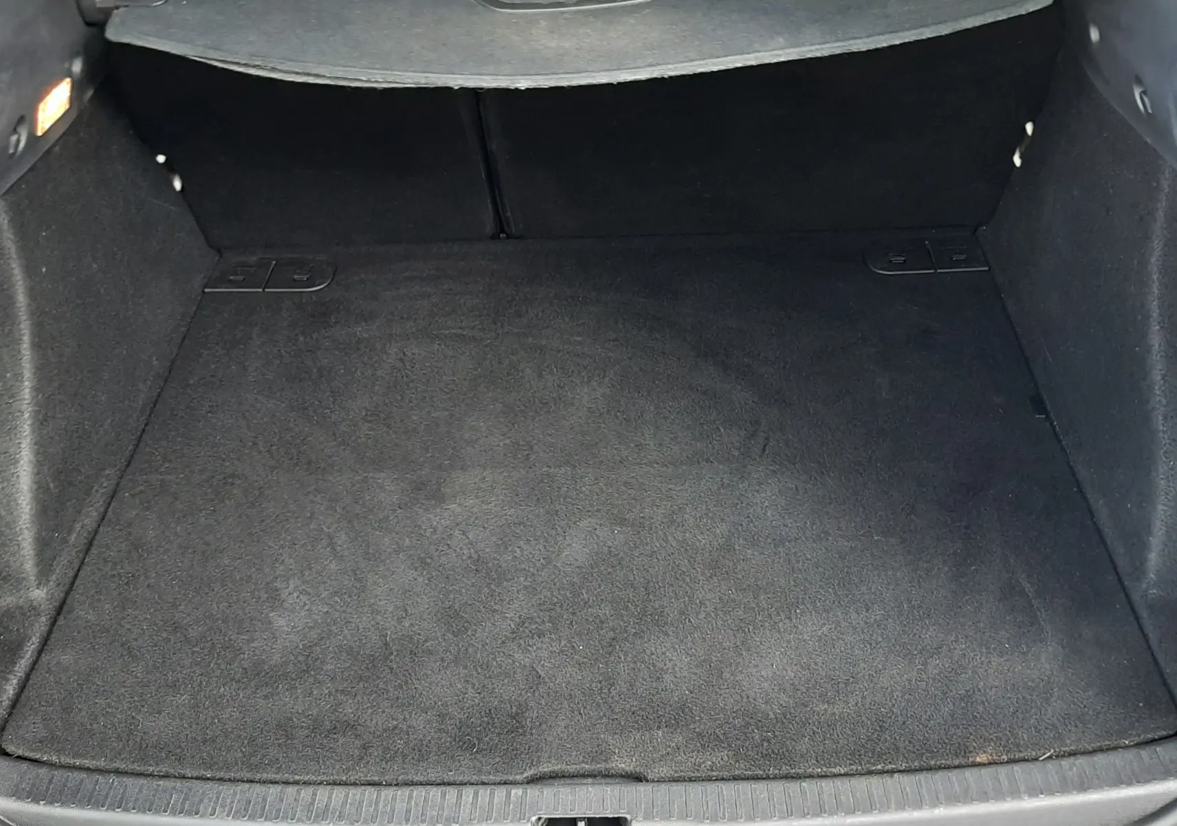 Coffre ouvert vu de l'arrière d'une Renault Clio IV Estate beige, montrant l'espace de chargement et la plage arrière.