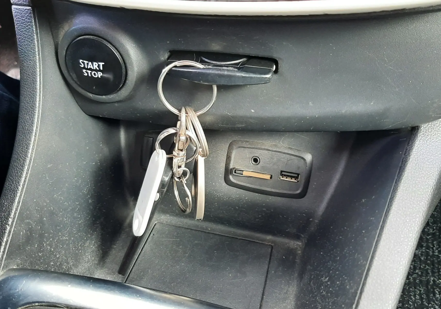 Gros plan sur la console centrale de la Renault Clio IV Estate beige, avec clé insérée et bouton Start/Stop visible.