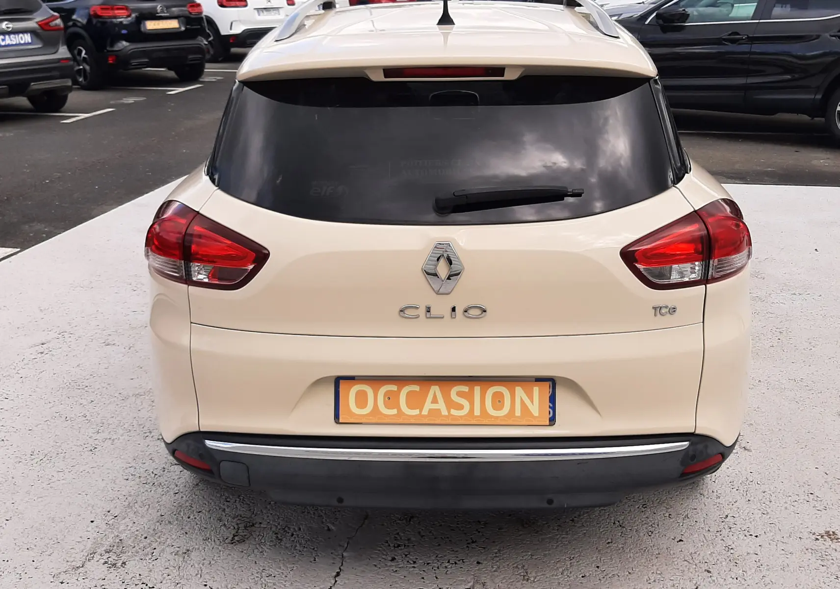 Vue arrière d'une Renault Clio IV Estate beige de 2016 avec vitres teintées et plaque "Occasion" visible.
