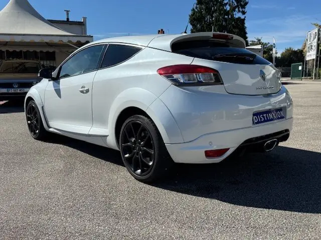Renault Mégane III Coupé 2.0T 265cv RS blanc nacré en 3/4 avant droit, jantes noires et calandre noire distinctive.