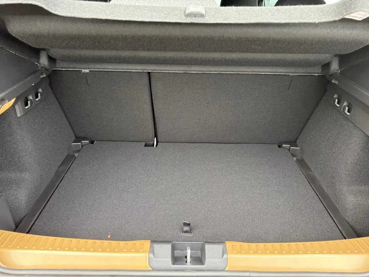 Coffre ouvert de la Dacia Sandero Stepway 2025 Beige Safari, montrant le plancher plat et les finitions intérieures grises.